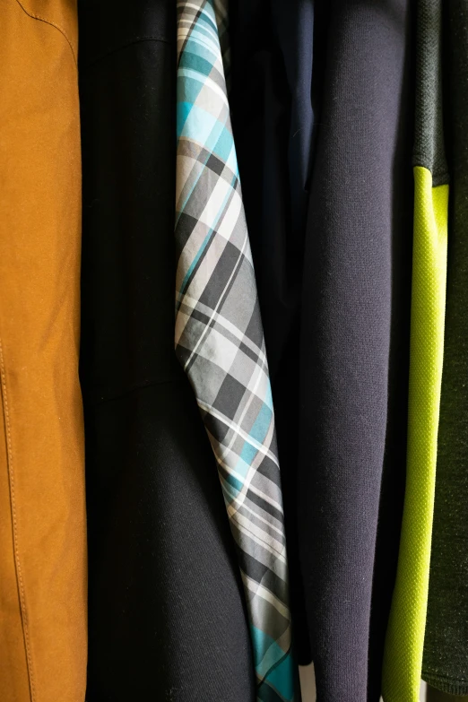 some different ties hang on top of a coat rack