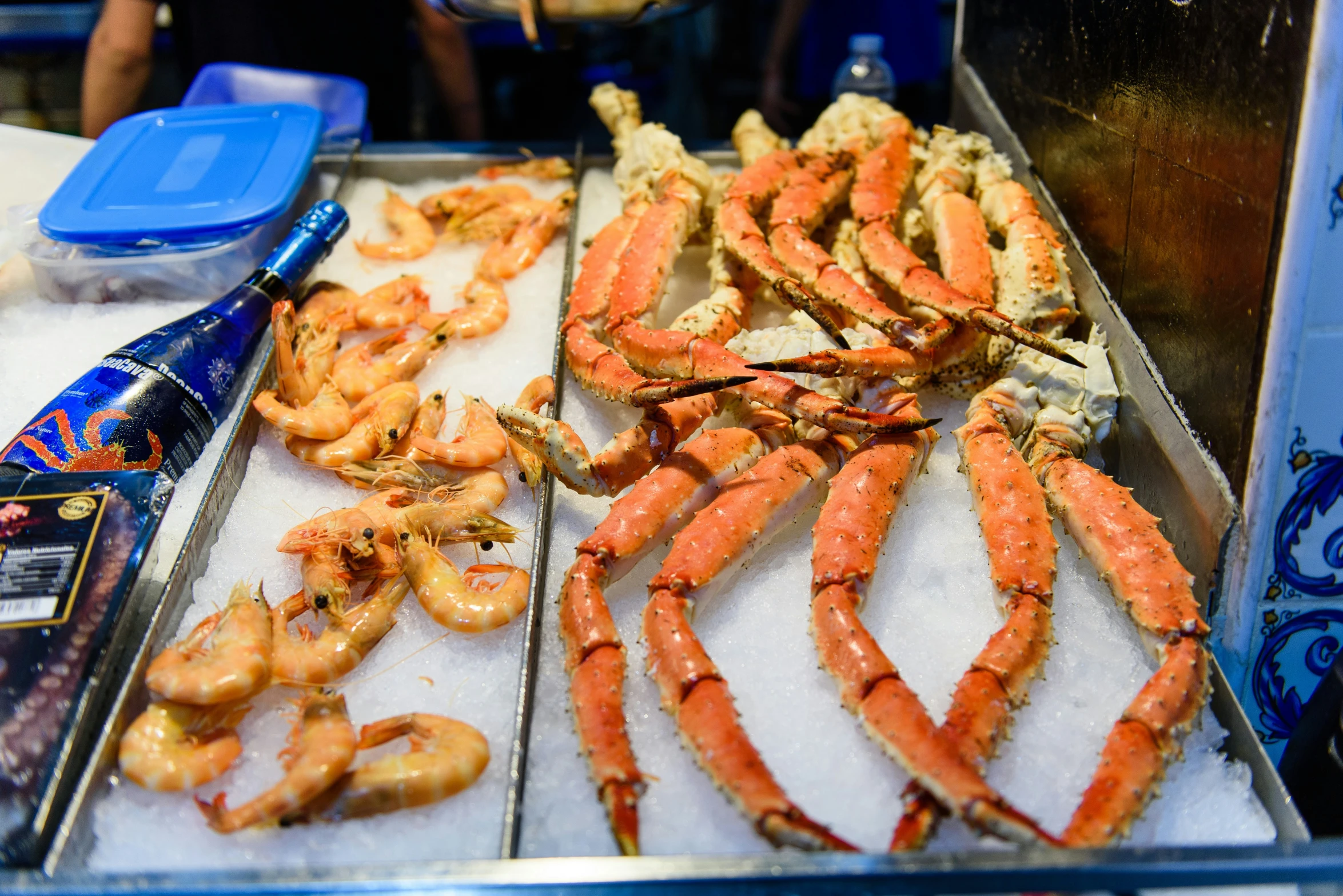 an array of crab legs in ice with tongs