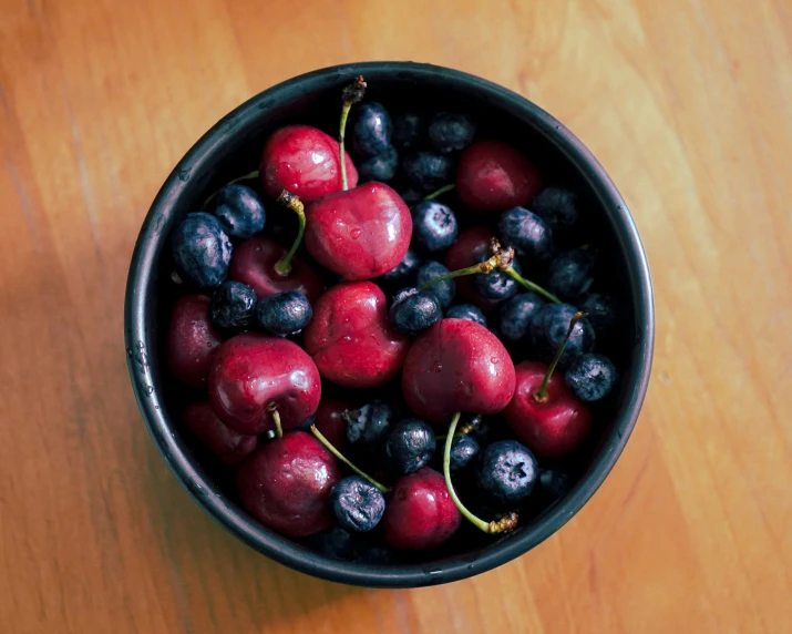 black cherries and blueberries in a bowl on a table