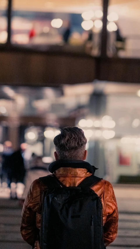 a man in an orange jacket is looking at some streetlights