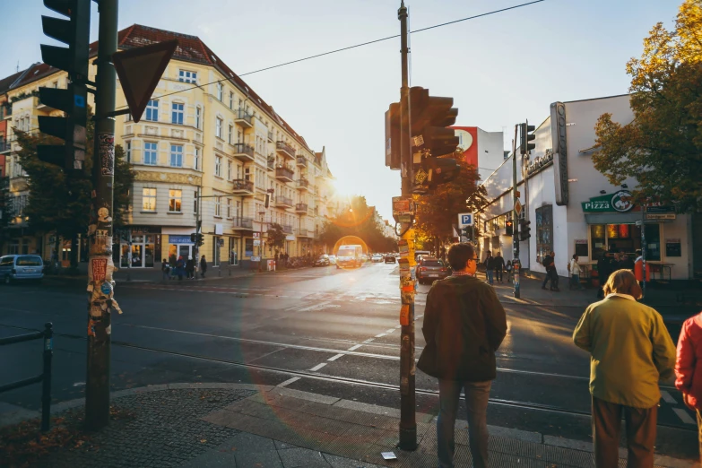 a couple of people standing on a corner next to a traffic light