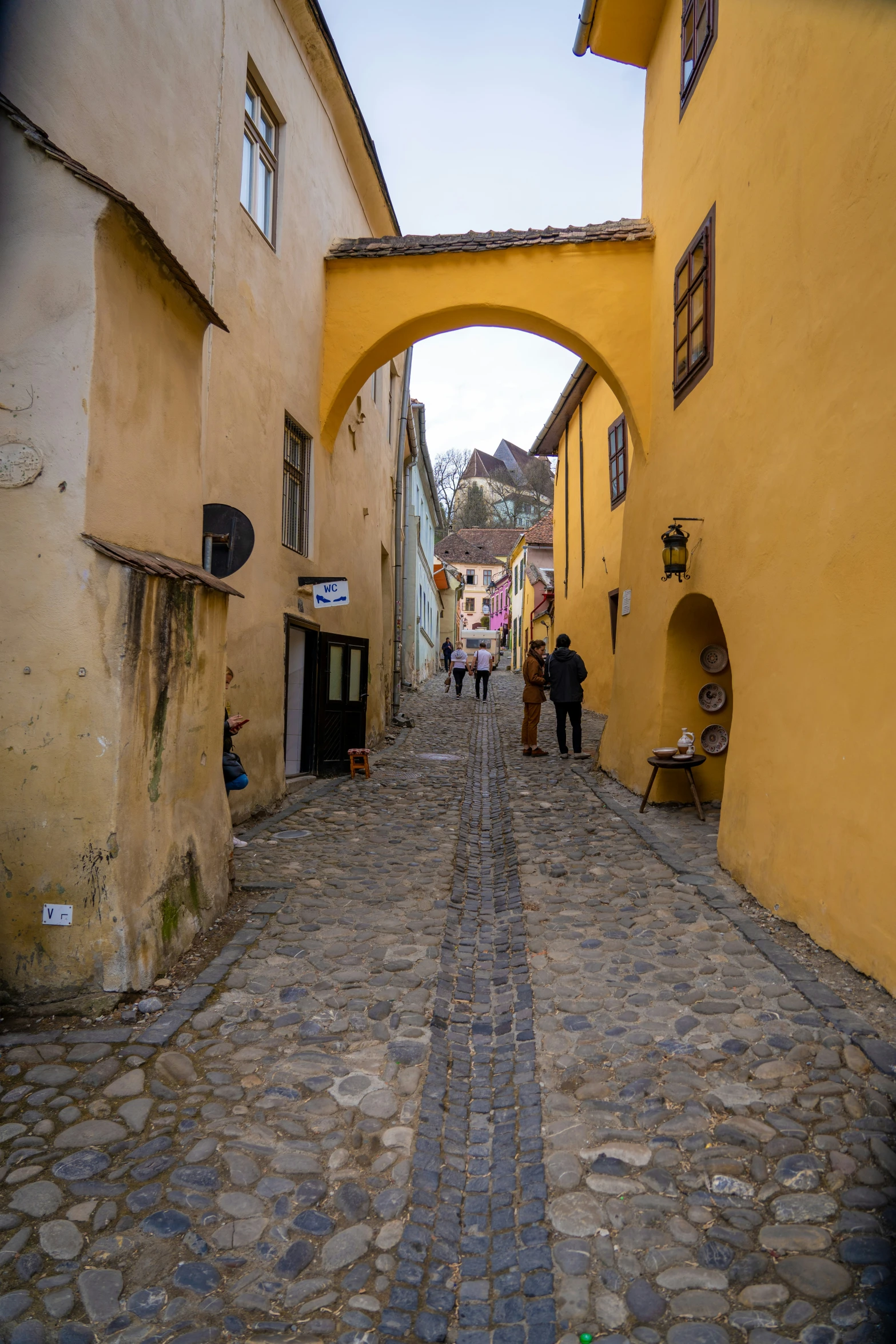 there are several people walking down the narrow alleyway