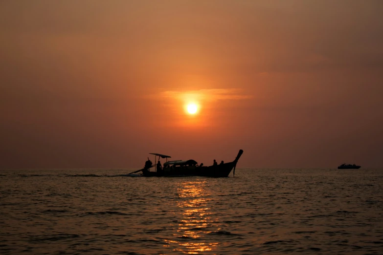 the sun rises over an ocean as people are rowing their small boat