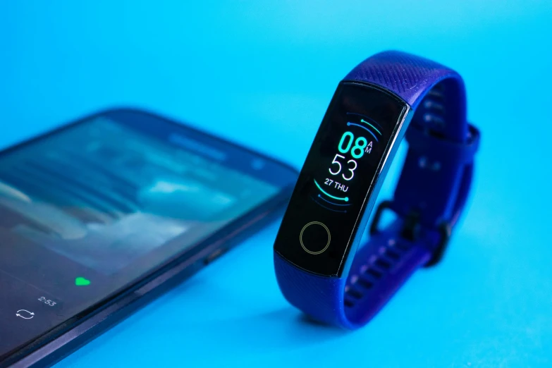 a fitness activity celet is displayed next to an galaxy note 5 smartphone