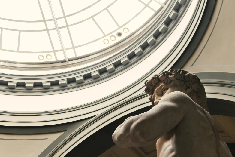 a marble angel sits next to a domed window in a building