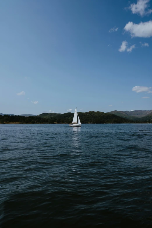 white boat in large body of water with mountains in the background