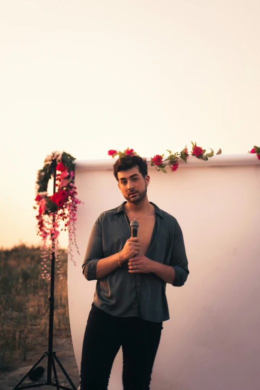 a person standing with a microphone near a white wall