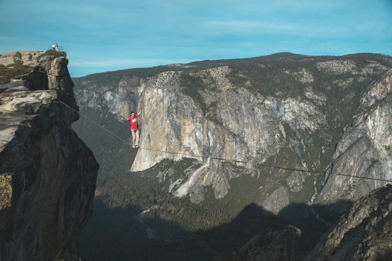 a person on top of a cliff with mountains in the background