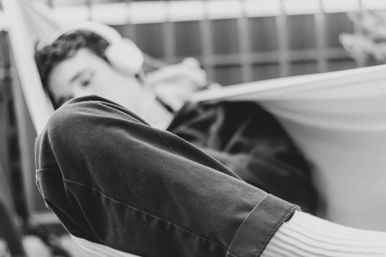 a man sitting in a hammock with his hand resting on a bag