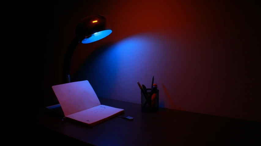 an open laptop sits on a desk in a darkened room