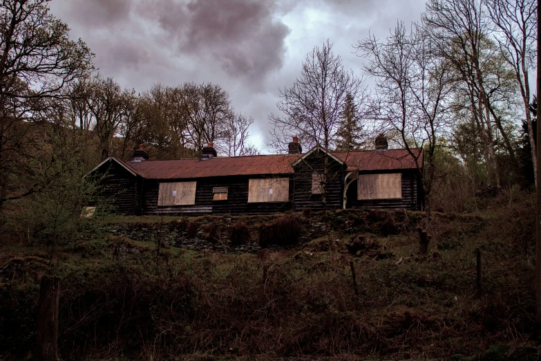 an old house stands on a tree - covered hill