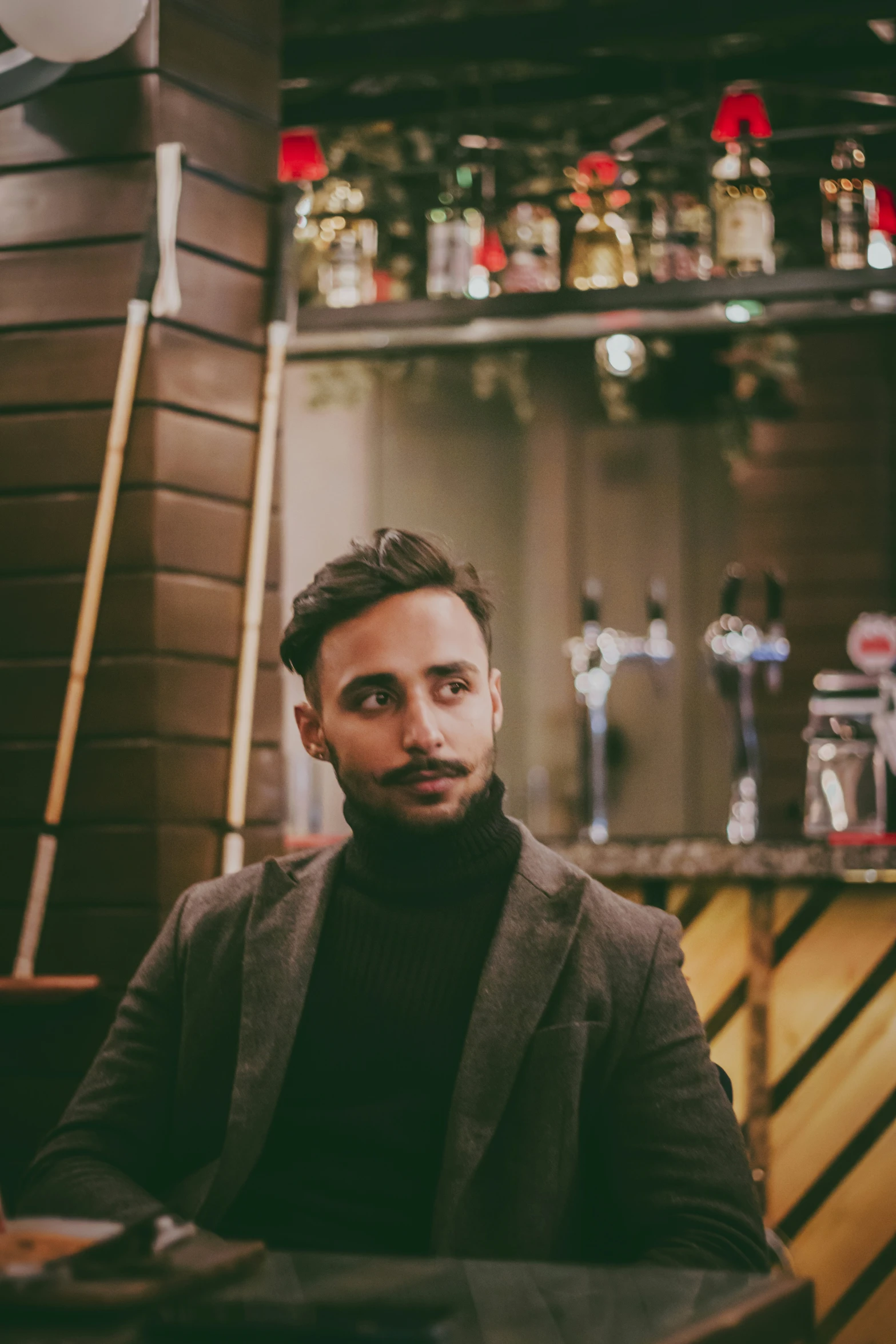 a man wearing a black turtle neck standing behind the bar