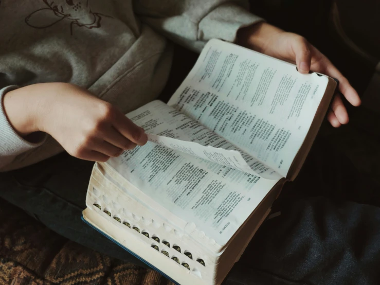 the hands of a child holding a book open