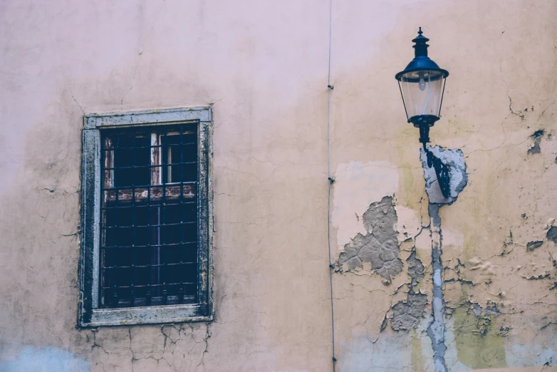 an old fashioned light next to a street lamp and wall