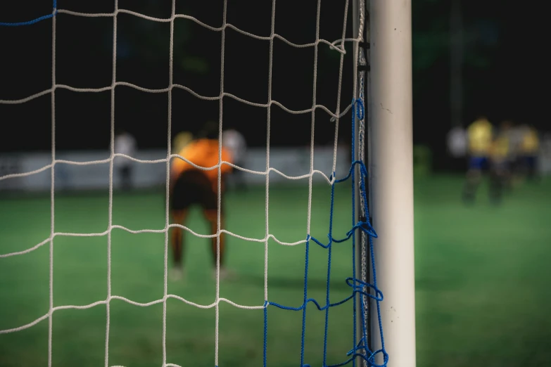 a close up of a goal post with a soccer ball on the field in the background