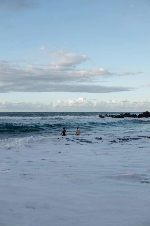 two surfers riding boards in the water on the beach