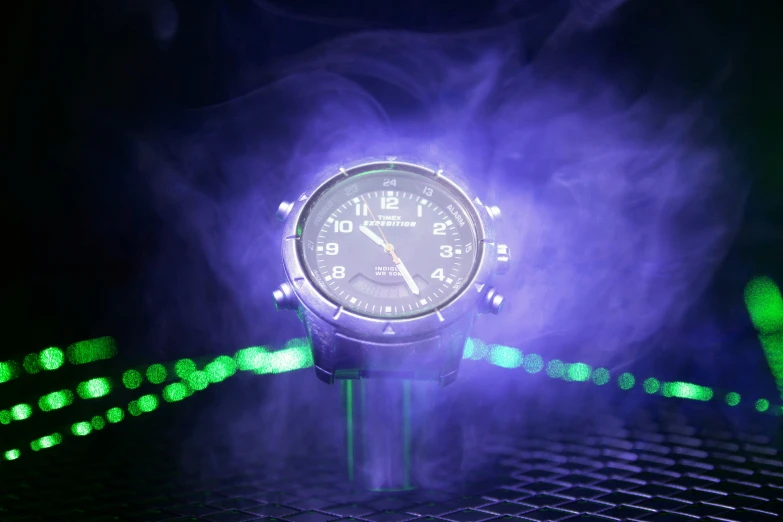 a clock is set on a metal surface surrounded by green light