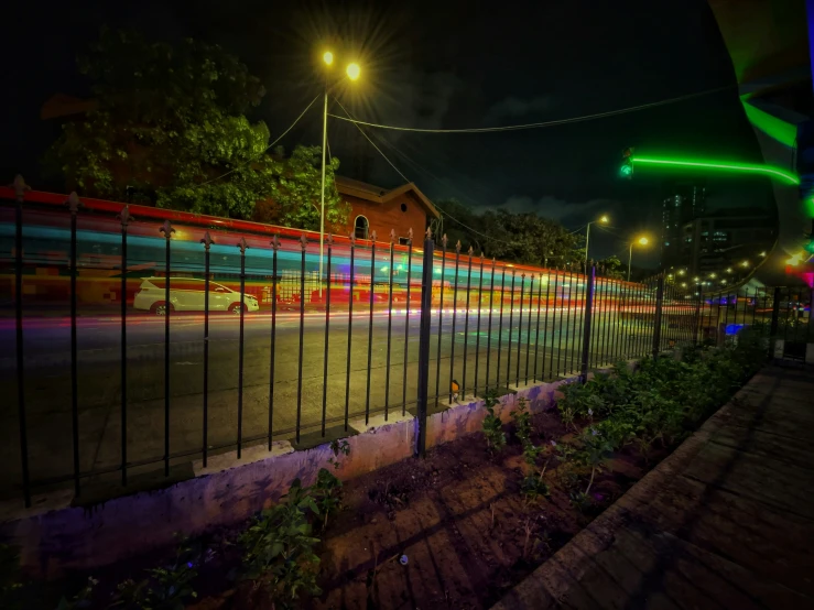 colorful light shines brightly on the ground next to a fence