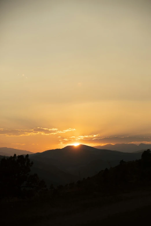 a plane flying over a hill at sunset