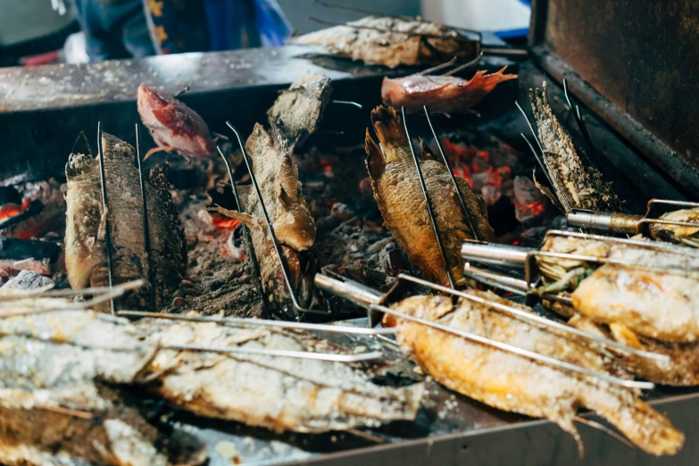 the grill is full of fish and  dogs