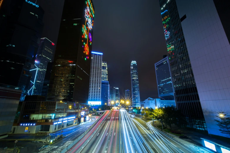 very long exposure of vehicles on a highway with tall buildings in the background