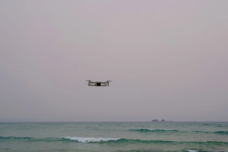 a small white and gray airplane flies over the ocean