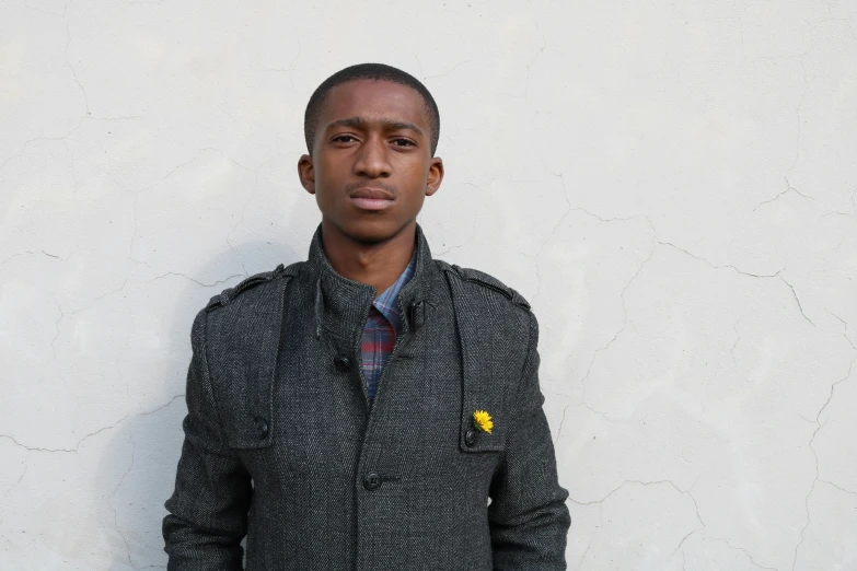 a young man standing with a coat and plaid shirt