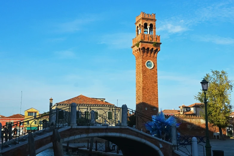 the bridge on the canal is near a very tall tower