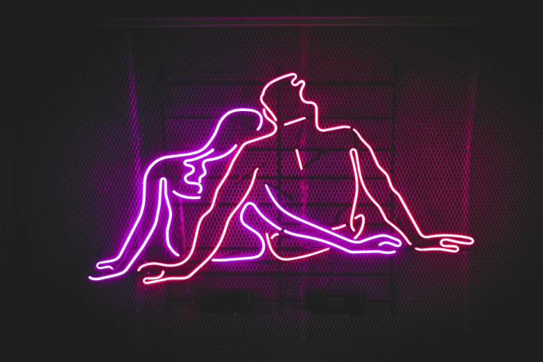 a man and woman sitting next to each other on a neon sign