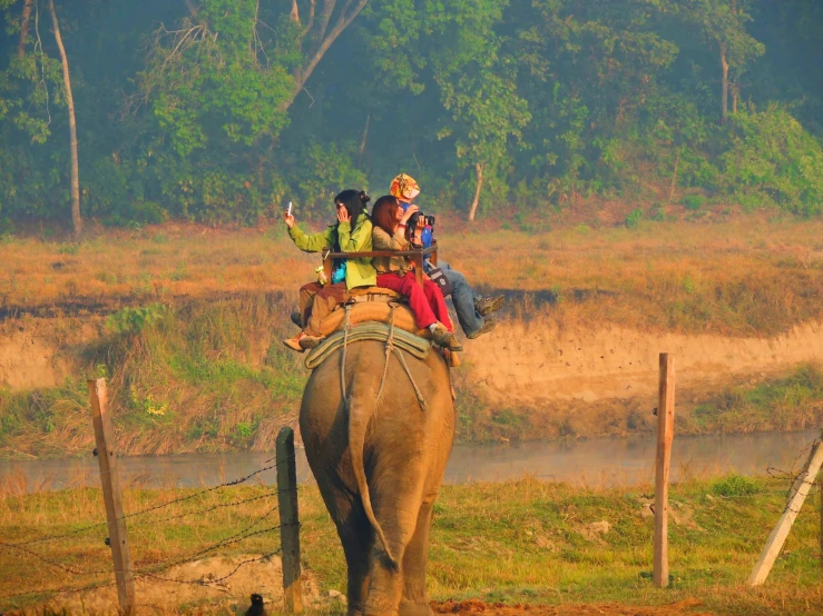 two people riding on an elephant and waving