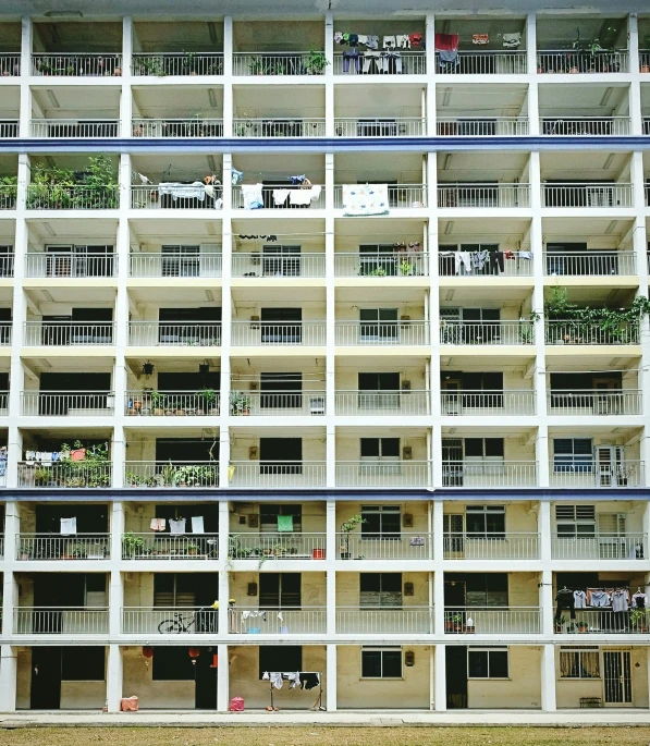 the front of a white building with balconies and plants