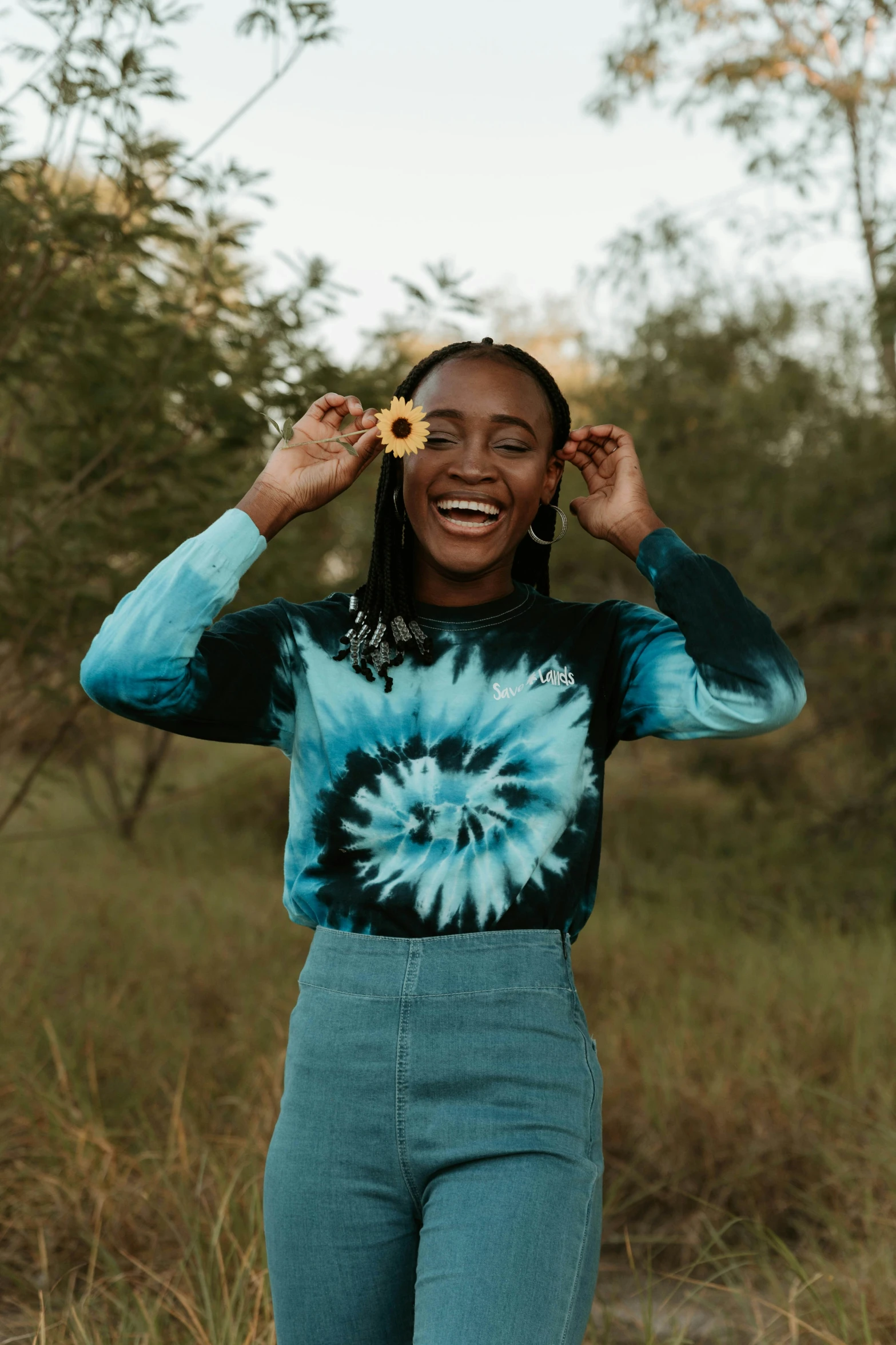 a woman in green shirt smiling and holding up her flower