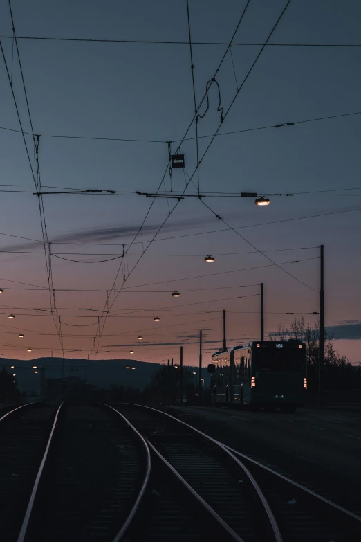 some train tracks and some buildings with wires above