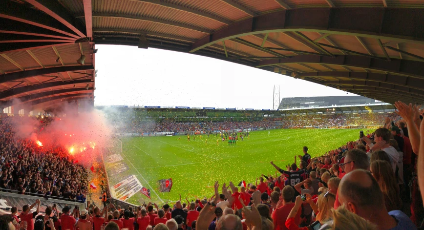 a soccer field full of people, with red and yellow confetti pouring from the stands