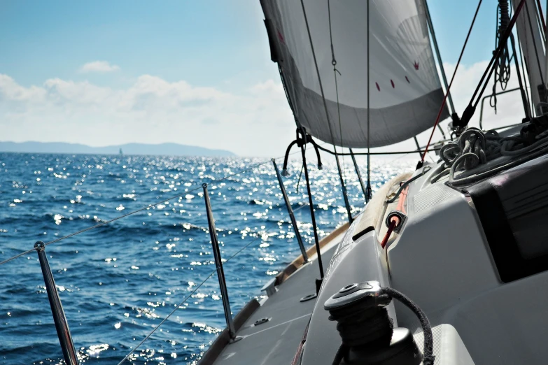 a sailboat that has sails down and blue water