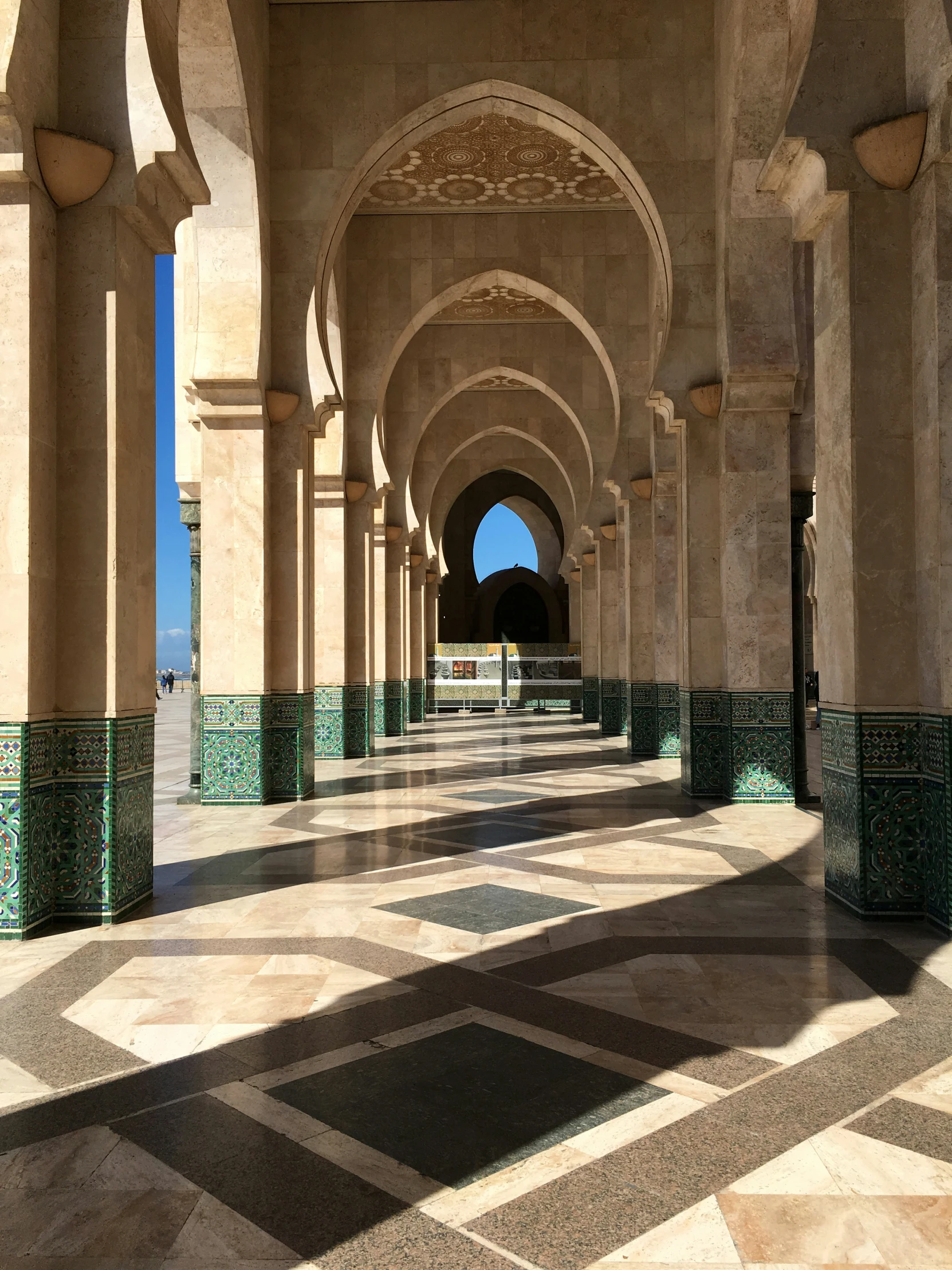 the tiled walkway under an archway with blue sky in the background
