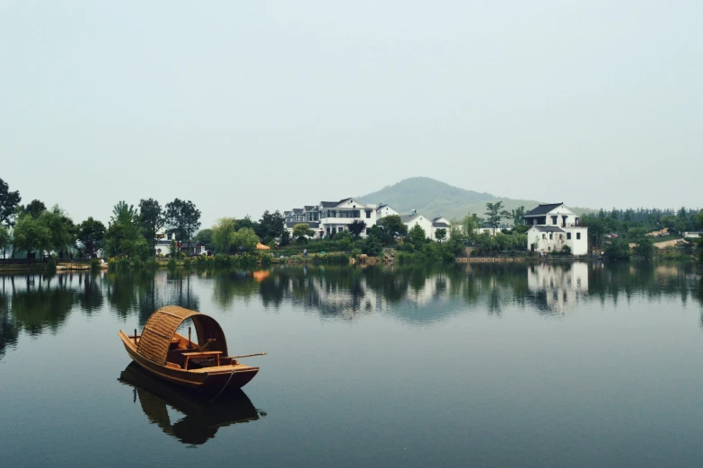 an empty boat on water with houses in the background