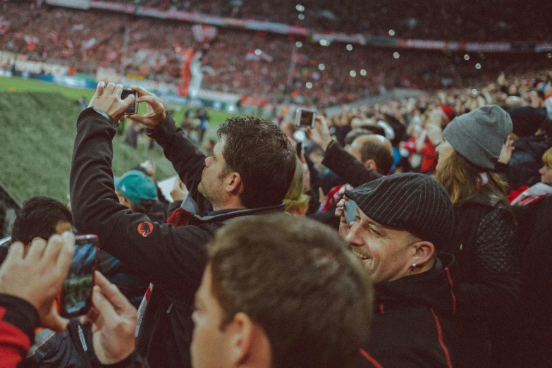 fans at a crowded football stadium are taking pictures