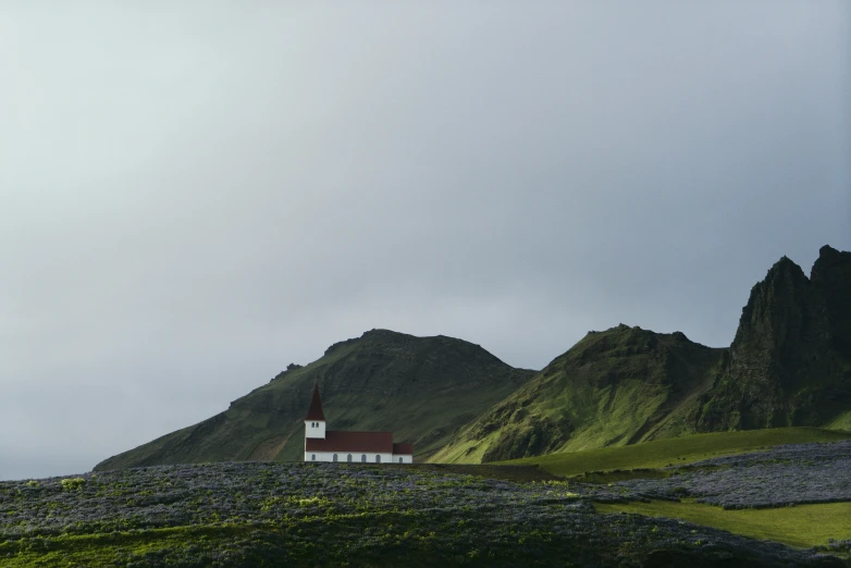 a red and white lighthouse next to large green mountains