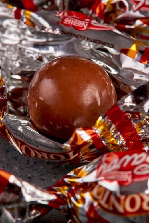 a chocolate ball lies in foil wrapped candy