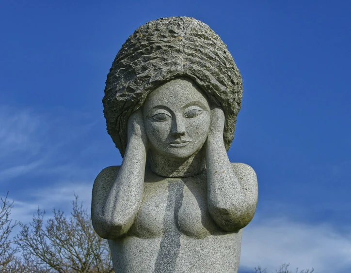 the statue is sitting on the hill with its head down