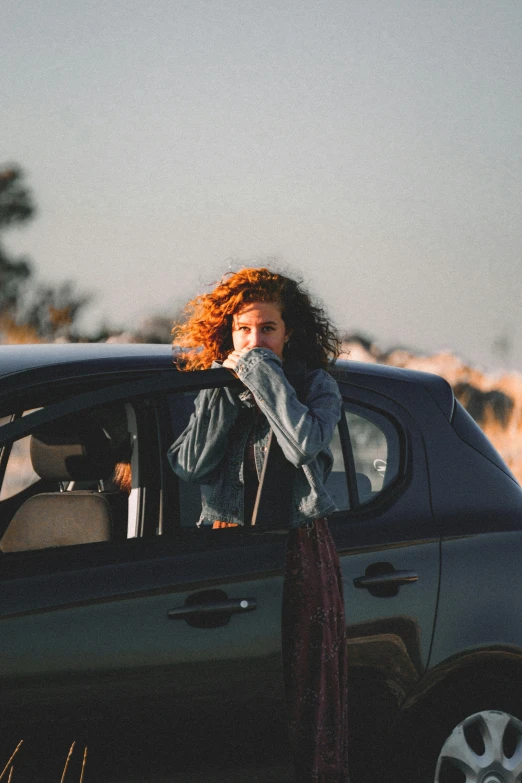 a woman standing next to a black car