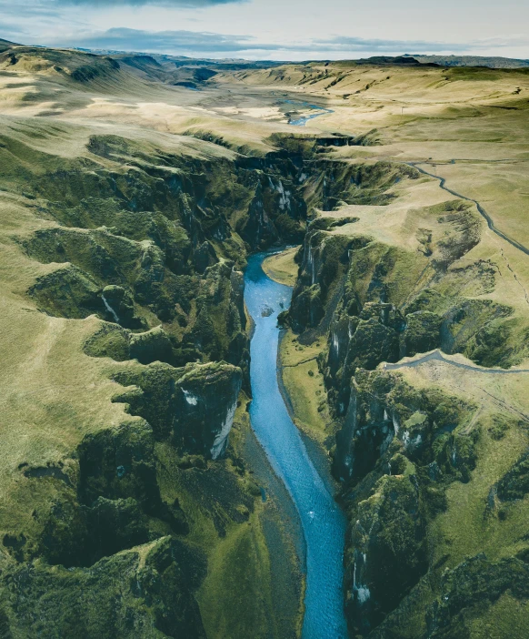 a river surrounded by green hills with a blue stream