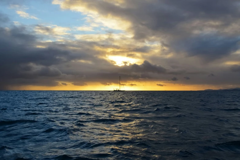 the sun is rising over the ocean and clouds