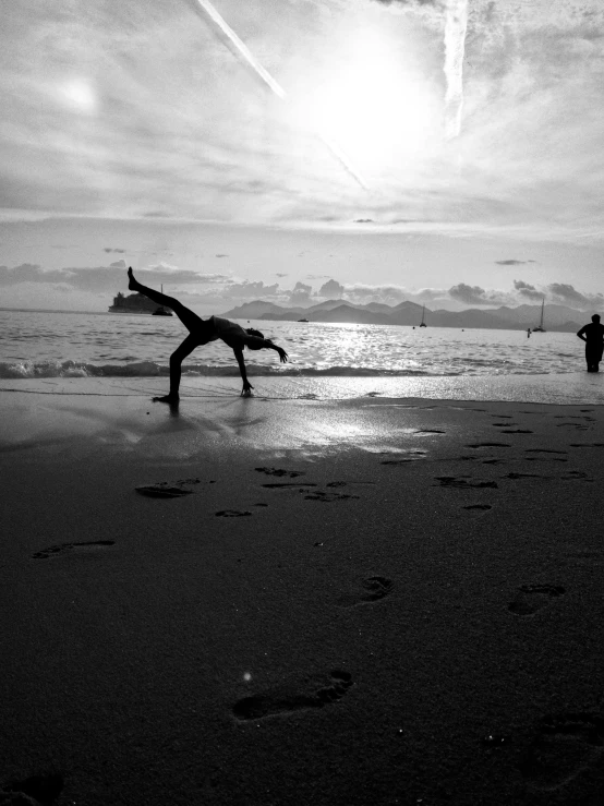 black and white pograph of people standing on the beach near ocean