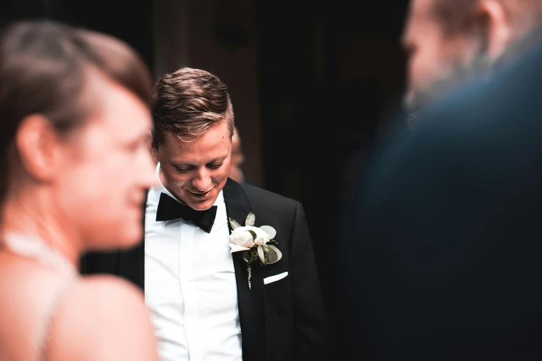a man in a tuxedo looks down at his bride