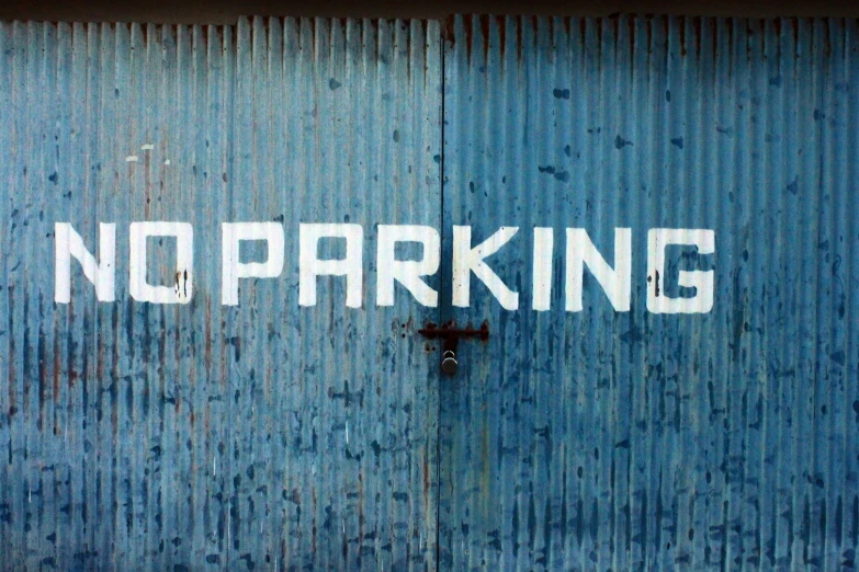 no parking sign on blue corrugated steel wall