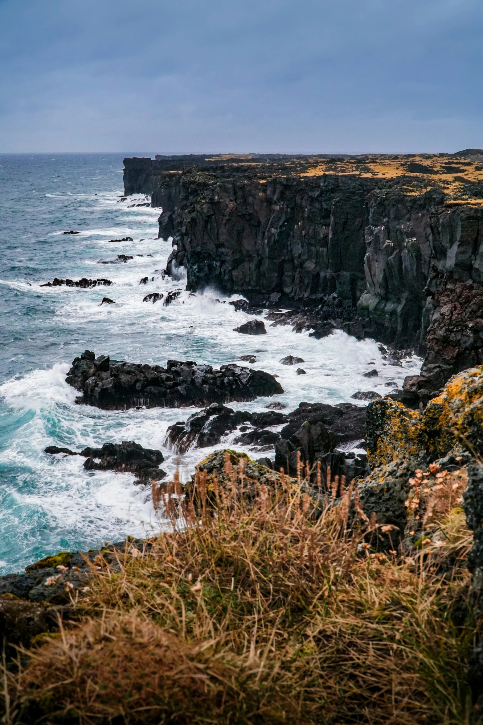 a sea cliff with a rough coastline with rocks below