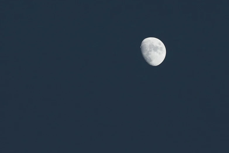 a very pretty white half moon in a blue sky