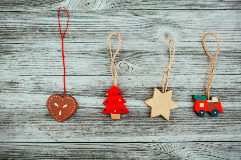 three ornaments hanging from strings on a wooden surface